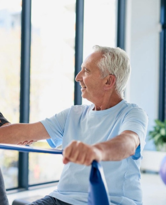 Senior bei ergotherapeutischem Training mit Theraband zur Förderung von Kraft und Beweglichkeit