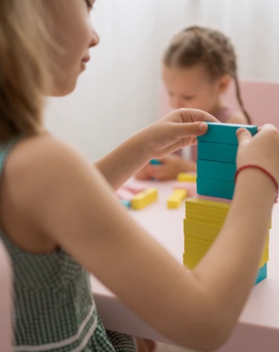 Kind bei ergotherapeutischer Förderung mit Stapelspiel zur Verbesserung der Feinmotorik