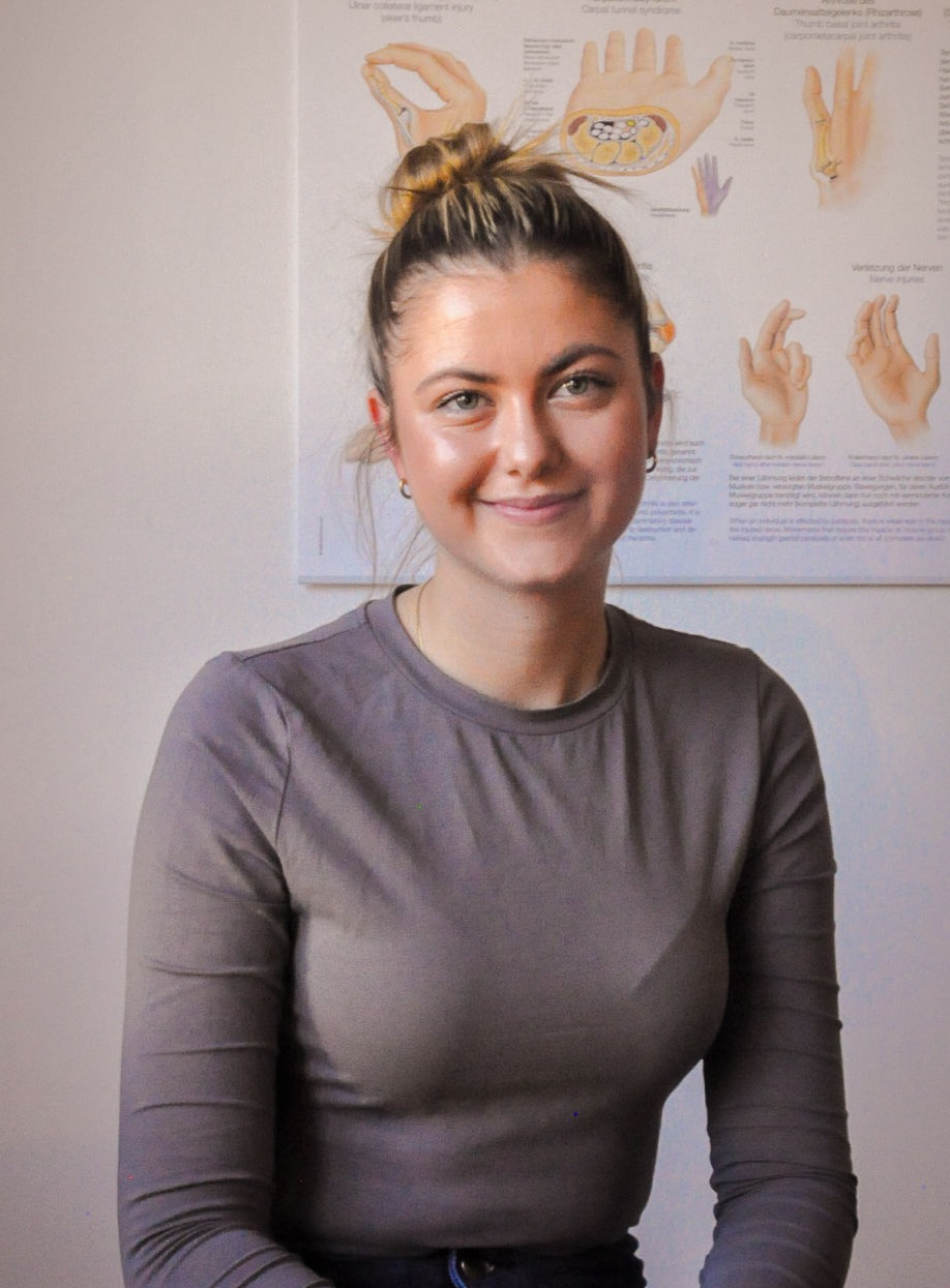 Portrait noch Emilia vor einem Anatomieposter der Hand