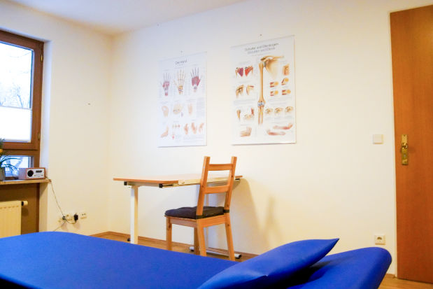 Behandlungsraum der Ergotherapie mit Therapieliege und Anatomiepostern